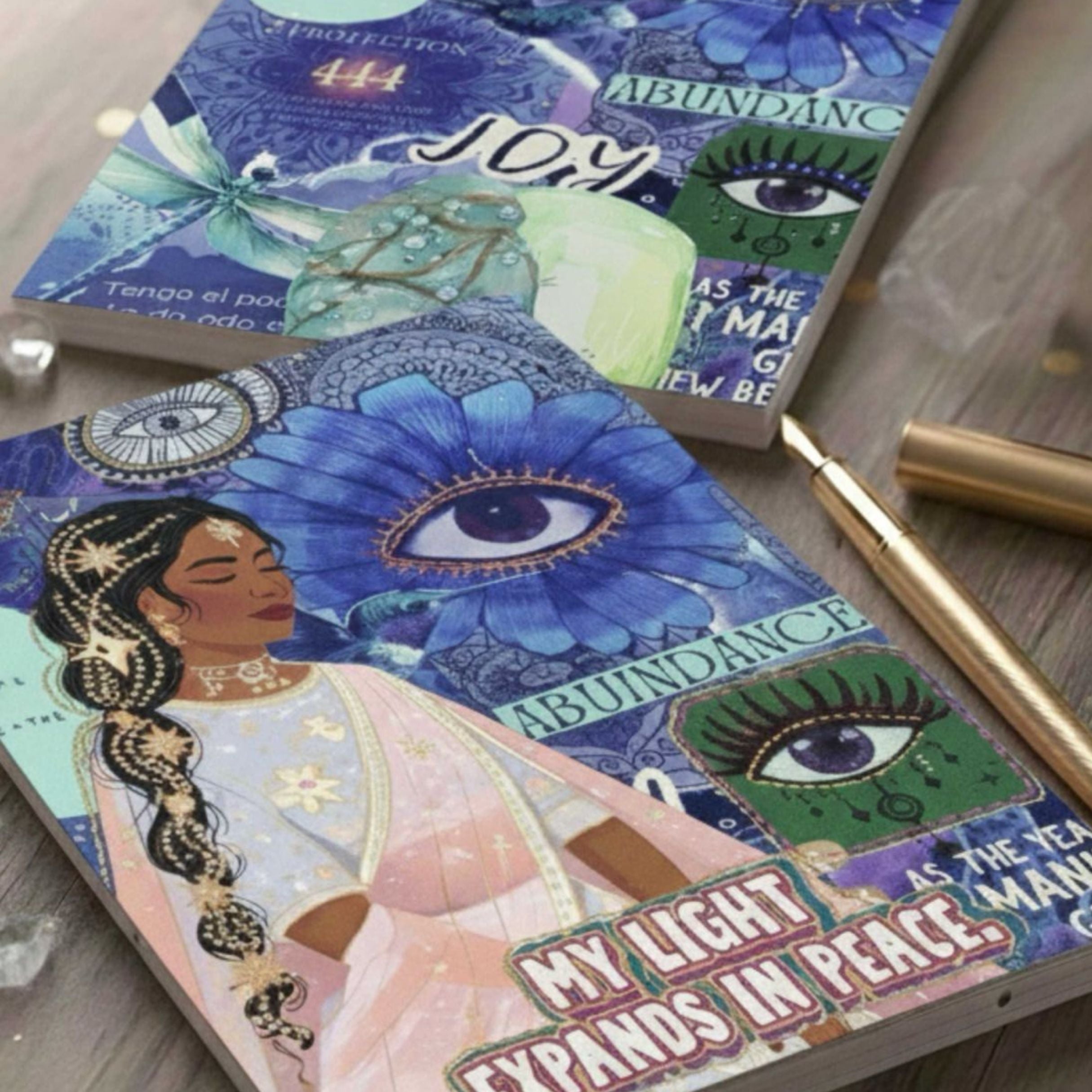 Joy abundance manifestation journal with illustrated cover, styled with candle, crystals, dried flowers and soft fabric background