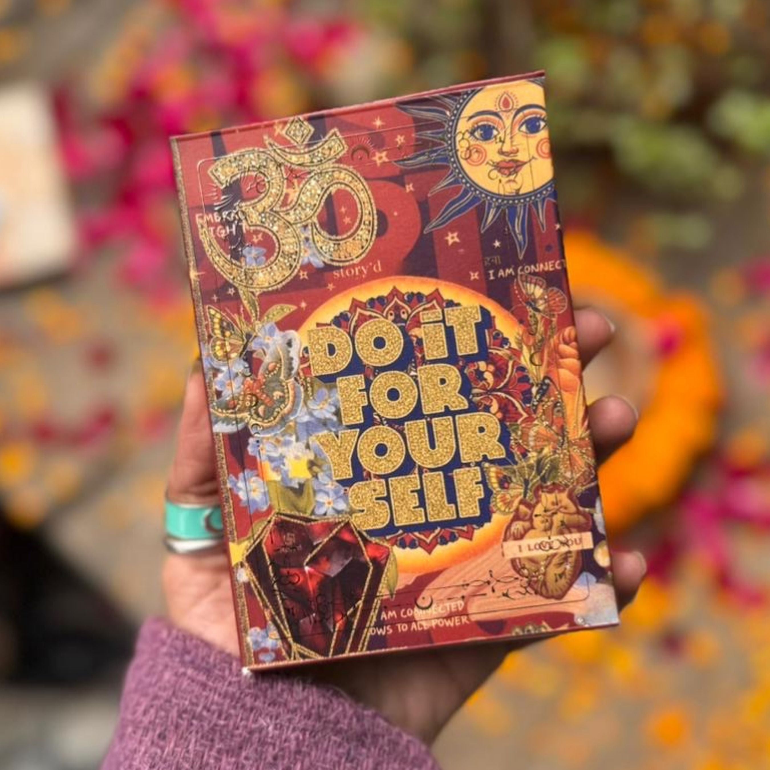 Decorative book titled 'Do It For Yourself' held by a person with a colorful blurred background.
